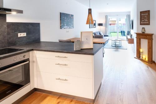 a kitchen with white cabinets and a black counter top at Garten-Appartement Ski&Nature "Kesselspitze" in Mauterndorf