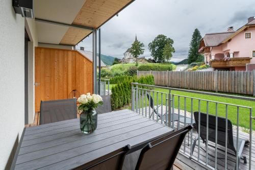 a vase of flowers on a wooden table on a balcony at Garten-Appartement Ski&Nature "Kesselspitze" in Mauterndorf