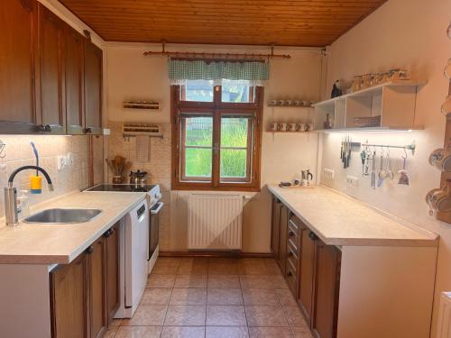 a large kitchen with a sink and a window at Roubenka Jeseníky in Břidličná