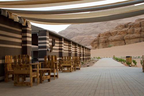 eine Terrasse mit Tischen, Stühlen und einem Berg in der Unterkunft Desert Season Camp in Wadi Rum