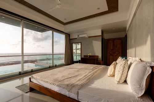 a bedroom with a bed with a view of the ocean at StayVista's Casa Bella - Sea-View Villa with Infinity Pool, Jacuzzi, Games, Entertainment, and Spa Room in Alibaug
