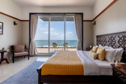 a bedroom with a bed with a view of the ocean at StayVista's Casa Bella - Sea-View Villa with Infinity Pool, Jacuzzi, Games, Entertainment, and Spa Room in Alibaug