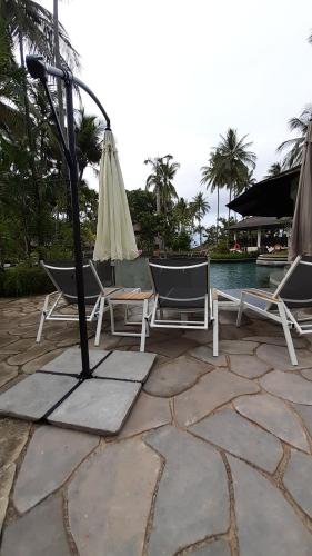 a patio with two chairs and an umbrella at Nongsa Village in Nongsa