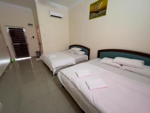 two beds in a room with white walls at DNELAYAN BEACH RESORT in Masjid Tanah