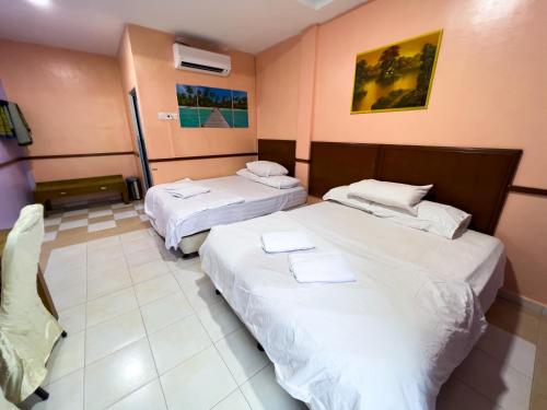 two beds in a hotel room with white sheets at DNELAYAN BEACH RESORT in Masjid Tanah