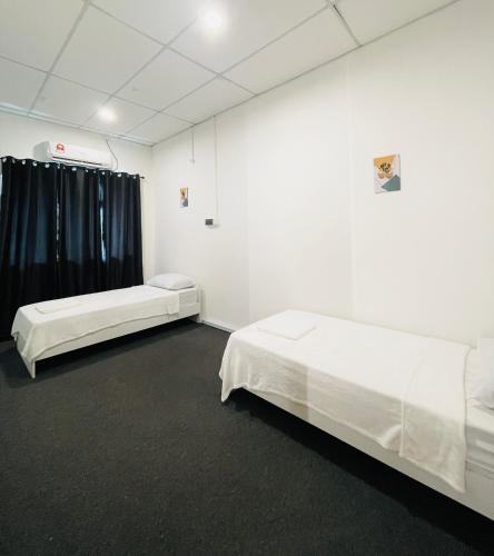two beds in a white room with black curtains at AK Greenrise Meru in Ipoh