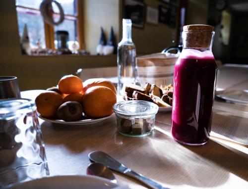 a table with a plate of oranges and a bottle of juice at Gite Auberge Les Cascades in La Mongie