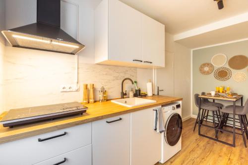 a kitchen with white cabinets and a sink at Zentral Boxspringbetten Garage Rhein in Bonn