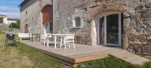 a wooden deck next to a stone building with a table and chairs at LA Grange Aux Etangs 