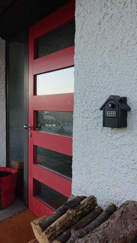 une porte rouge avec une boîte aux lettres à côté d'une maison dans l'établissement Haus Rosebud, à Weilheim