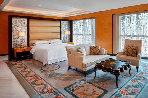 Sheraton Hohhot Hotel في هوهوت: غرفة نوم بسرير واريكة وطاولة