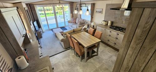 a kitchen and dining room with a table and a couch at Hot Tub Lodge Cornwall - Meadow Lakes Holiday Park in St Austell
