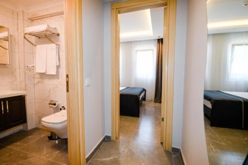 a bathroom with a toilet and a bedroom with two beds at Swan Boutique Hotel in Bodrum City