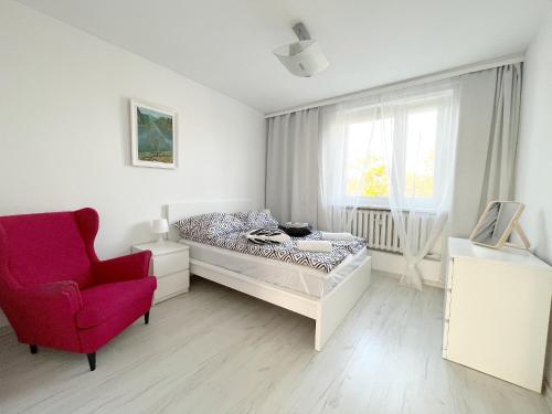 sypialnia z łóżkiem i czerwonym krzesłem w obiekcie 19 Gdynia Centrum - Apartament Mieszkanie dla 8 os w mieście Gdynia