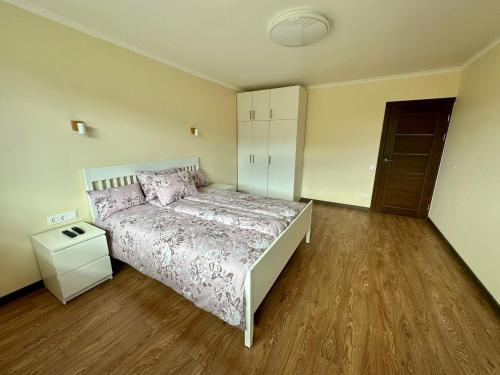 1 dormitorio con 1 cama y suelo de madera en Swan City Family Apartment, en Gulbene