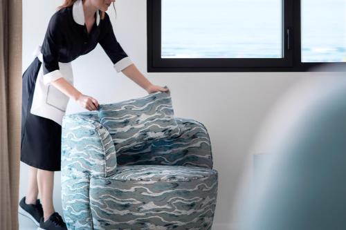 a woman is standing next to a camouflage chair at Hotel Byron in Forte dei Marmi