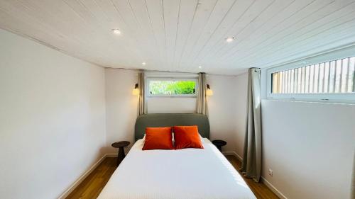a bedroom with a bed with two orange pillows on it at Villa Jacqueline, la baie du Mont-Saint-Michel in Dragey