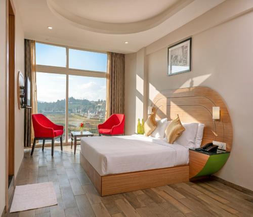 a hotel room with a bed and red chairs at Mango Hill Central Ooty in Ooty