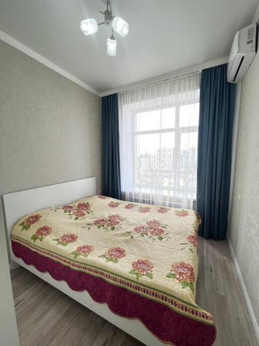 1 dormitorio con 1 cama y una ventana con cortinas azules en Прекрасное местечко Barys City, en Taldykolʼ