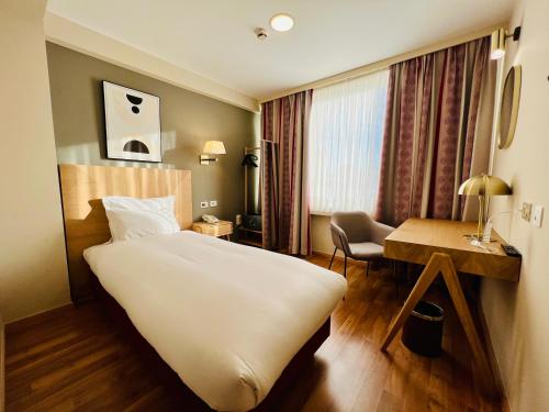 a hotel room with a large bed and a desk at Bedford Hotel & Congress Centre Brussels in Brussels