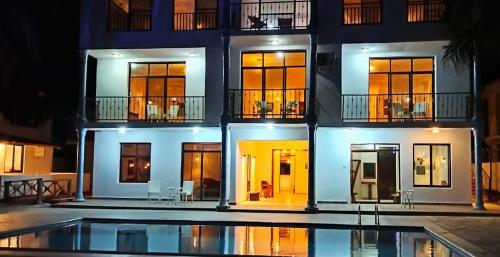 un edificio con piscina di fronte ad esso di BIANCO AZZURRO Hotel & Restaurant a Pwani Mchangani