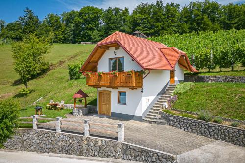 ein kleines weißes Haus mit einem Balkon und einem Zaun in der Unterkunft Vineyard Cottage Krivic - Happy Rentals in Trebelno