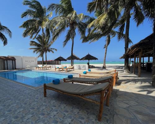 a resort with a pool and palm trees on the beach at BIANCO AZZURRO Hotel & Restaurant in Pwani Mchangani