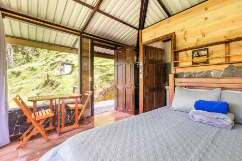 a bedroom with a bed and a table and chairs at Hotel Rivel - Restaurant & Nature Retreat in Turrialba