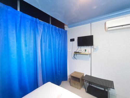 a bedroom with a blue curtain and a tv at Pen'U Cottages by RVH in Dungun