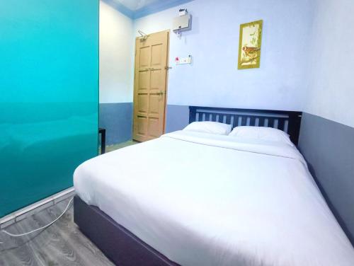 a bedroom with a white bed and a blue wall at Pen'U Cottages by RVH in Dungun
