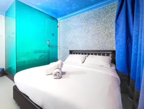 a bedroom with a large white bed with blue walls at Pen'U Cottages by RVH in Dungun