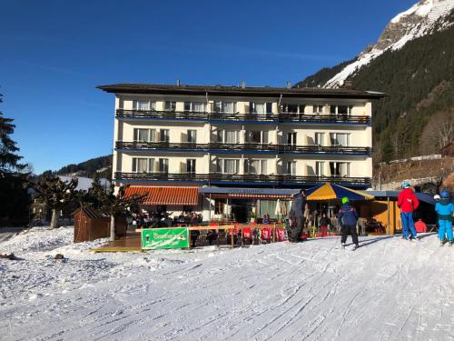 un hotel con gente parada en la nieve frente a él en Apartment with great view at Residence Brunner en Wengen