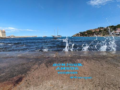 a sign written on the beach near the water at La perle de Collioure à 100 métres de la plage de sable fin avec piscine et parking in Collioure