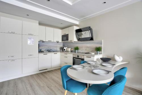 une cuisine avec une table blanche et des chaises bleues dans l'établissement Val Détente - Appartement à proximité immédiate de la plage, à Pléneuf-Val-André
