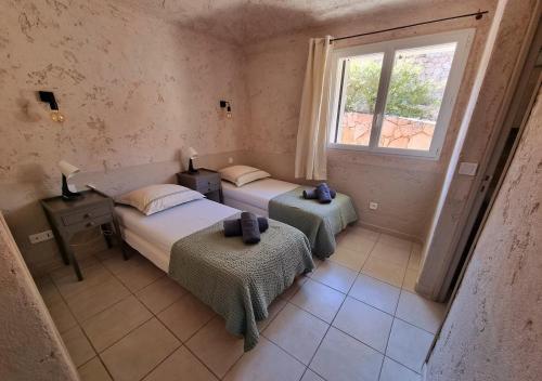 1 dormitorio con 2 camas y ventana en CORSACASA Villa in Palombaggia sea view en Porto Vecchio
