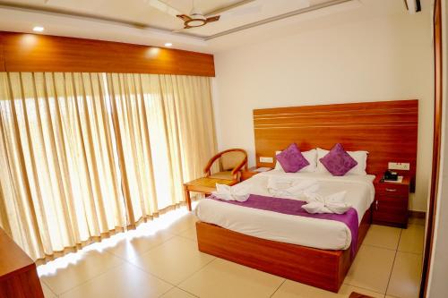 a bedroom with a large bed with purple pillows at The Lake View Munnar in Munnar