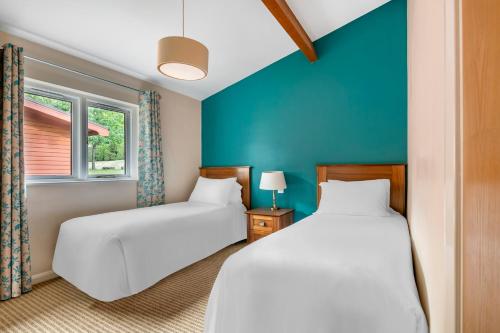 2 łóżka w pokoju z niebieskimi ścianami w obiekcie Wychnor Park Country Club w mieście Barton under Needwood