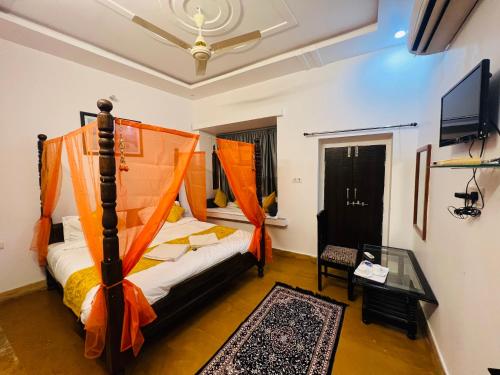 a bedroom with a bed with an orange canopy at Hotel Dara & Camel Safari in Jaisalmer