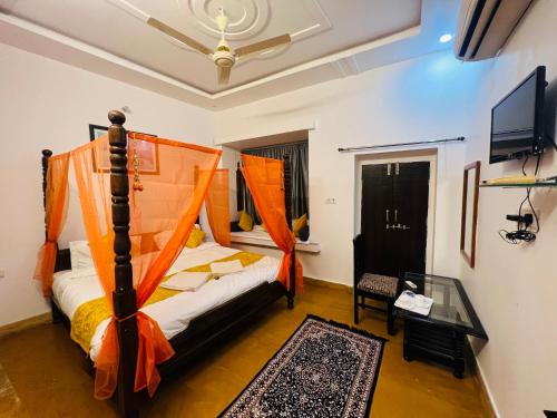 sypialnia z łóżkiem z pomarańczowym baldachimem w obiekcie Hotel Dara & Camel Safari w mieście Jaisalmer