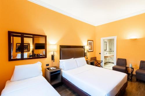 a hotel room with two beds and a mirror at Allegroitalia San Gallo Firenze in Florence