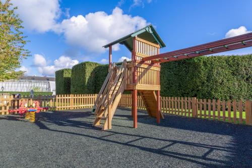 a wooden playground with a slide in front of a fence at Wychnor Park Country Club in Barton under Needwood