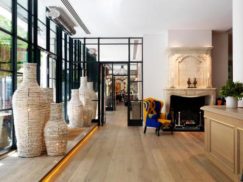 a living room with a fireplace and vases at Ham Yard Hotel, Firmdale Hotels in London