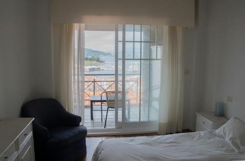 um quarto com uma cama, uma cadeira e uma varanda em Maravilloso apartamento con vistas al mar em Baiona