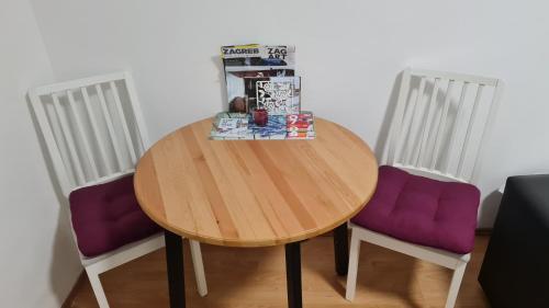 einem Holztisch mit zwei lila Stühlen neben einem Tisch in der Unterkunft Apartman "Britanac" in Zagreb