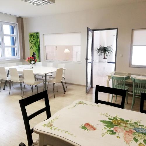a dining room with tables and chairs and windows at Guest House Factory in Malacky