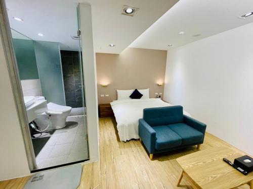 ein Hotelzimmer mit einem Bett und einem blauen Stuhl in der Unterkunft 森浩文旅 in Taipeh
