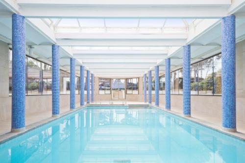 ein großer Pool mit blauen Säulen in einem Gebäude in der Unterkunft Hotel Best Delta in Maioris Decima