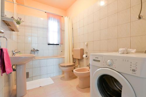 uma máquina de lavar roupa na casa de banho com um WC e um lavatório em Apartments Doda em Zadar
