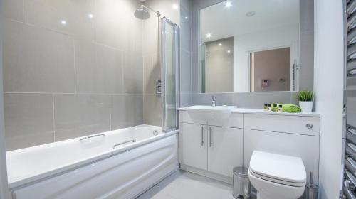 a bathroom with a white tub and a sink and a toilet at Andora Apartments in London