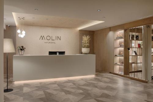 a lobby with a white counter and a sign on the wall at Naturhotel MOLIN in San Giovanni in Val Aurina
